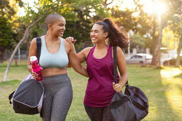 Two friends walking home together after a workout, smiling in the evening light